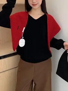 Detail of red knitted shawl layered over black V-neck top and brown high-waist trousers
