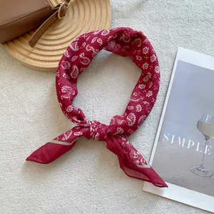 Detail of a silky red paisley square scarf tied as a necktie in a French vintage setting