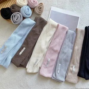 Flat lay of colorful handmade knit scarves showing detailed texture and woven labels