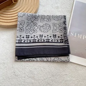 Close-up of paisley pattern square scarf on beige textured carpet with props