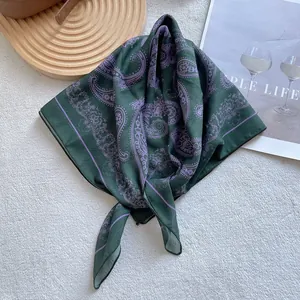 Detail of dark green paisley square scarf with silk texture and lavender floral pattern