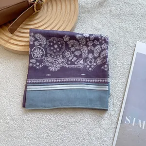 Detail view of purple and blue paisley silk scarf with refined stitching on white texture