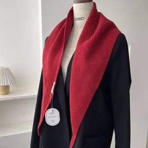 Close-up of red ribbed knit shawl with triangular design and texture on a mannequin