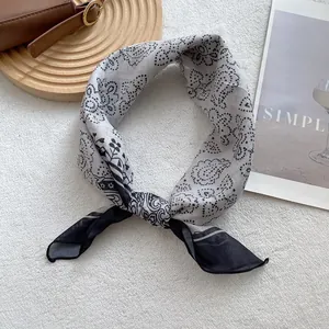 Detail of knotted black and white paisley square scarf on white textured background