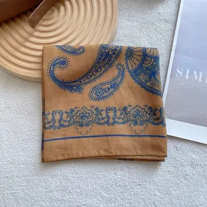 Close-up of beige paisley silk square scarf with vintage blue floral pattern and hemmed edges