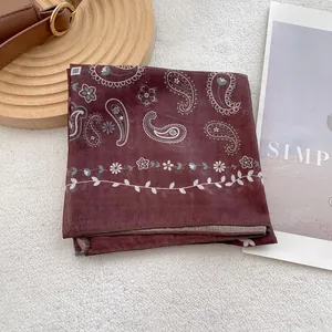Detail of red paisley silk scarf with intricate vintage patterns on soft white texture