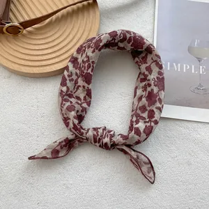 Detail of vintage floral silk scarf with red patterns on cream fabric tied elegantly