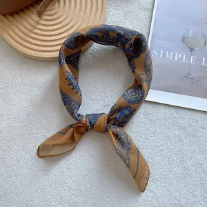 Detail of paisley print silk scarf in ginger yellow and dark blue with smooth texture