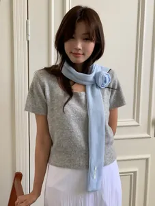 Detail of light blue knit scarf with handmade 3D floral rose knot for elegant styling
