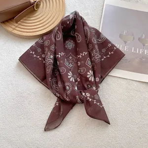 Detail of coffee paisley silk scarf with daisy pattern on minimalist white background