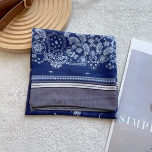Detailed view of dark blue paisley silk scarf with white floral patterns and striped edge