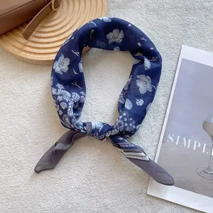 Macro shot of dark blue paisley silk scarf with floral patterns on a minimal tray