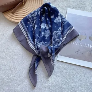 Close-up of silk-textured paisley scarf styled with brown bag on white rug