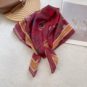 Detail of burgundy square scarf with bear prints and stripe edges on a magazine
