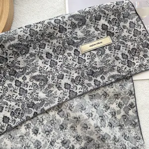 Detail of vintage paisley silk scarf with 'explore infinity' label and fine stitching