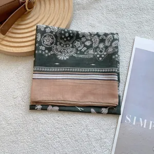 Detailed close-up of a paisley silk scarf with dark green patterns and pink block color