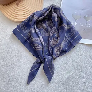 Detail of dark blue paisley silk scarf with beige patterns on soft white carpet
