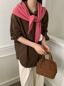 Chic pink chunky knit shawl styled over a dark brown long sleeve shirt and white trousers