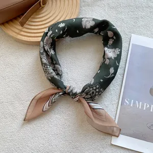 Close-up of knotted silk scarf featuring dark green paisley pattern and pink floral details