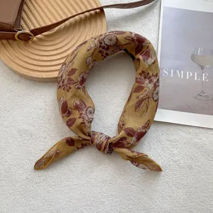 Close-up of vintage yellow silk scarf with botanical patterns and a tied knot detail