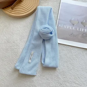 Detail of light blue knitted floral scarf featuring a white Hand Made fabric label