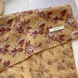 Detailed shot of yellow silk scarf featuring lemon prints and an explore infinity label