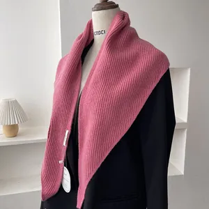 Detail of pink ribbed knit scarf texture with brand tag on black mannequin display