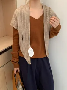Detail of beige ribbed knit shawl layered over caramel V-neck sweater on model