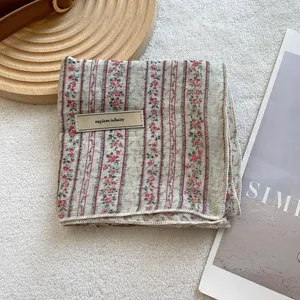 Detail of floral cotton linen headscarf featuring a leather label and rustic texture