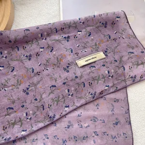 Detail of purple floral scarf showing breathable fabric texture and Explore labels