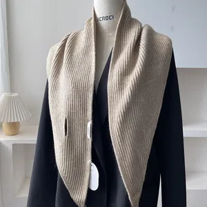 Detail of khaki ribbed knit shawl draped over a black suit with a focus on its soft texture