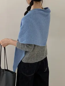 Detail of blue knitted shawl with vertical ribbed texture styled over a gray sweater