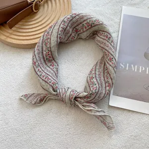 Detail of floral cotton linen headscarf tied in a bow on a vintage leather bag background