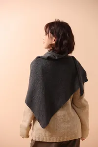 Detail of dark grey knitted shawl cape with thick texture and refined knitting pattern