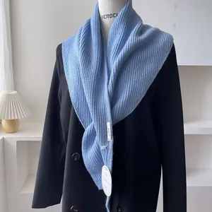 Detailed knit texture of light blue triangular shawl with woven label and tag