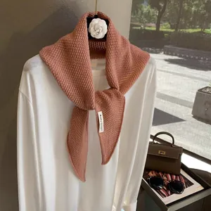 Detail view of pink wool knit scarf showing intricate waffle texture and MUCO brand label