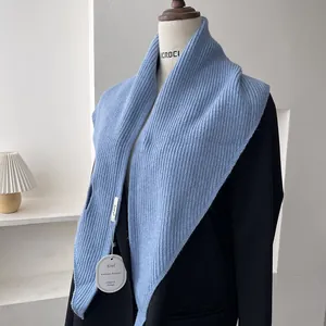 Detail of light blue ribbed knit shawl layered over a black blazer showing fabric texture