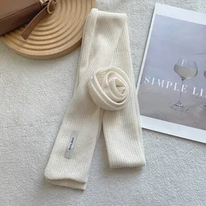 Detail of hand-made cream knit floral scarf featuring a crochet rose and textured pattern