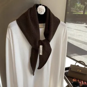 Detail of dark brown knit scarf showing 92% wool 8% cashmere texture and woven label