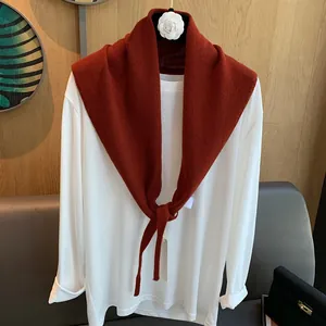 Eleganter Wollstrick-Schulterschal in Orange mit einer weißen Kamelien-Brosche