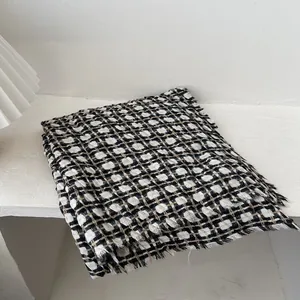 Detail of knit plaid scarf with frayed edges in black, white and brown tones