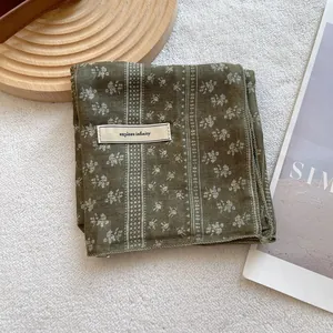 Detail of floral cotton linen headscarf with explore infinity label and stripe patterns