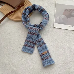 Detail van de gebreide Fair Isle-sjaal met leren logolabel in blauwgrijs design