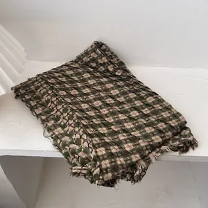 Detail of green and beige plaid knit scarf with unique crinkle texture and fringe edges