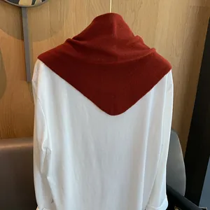 Detail eines dunkelroten Strickschals mit Rippenstruktur auf weißem Hemd