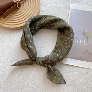 Detail of dark green floral silk scarf tied as a necktie on a stylish wooden tray