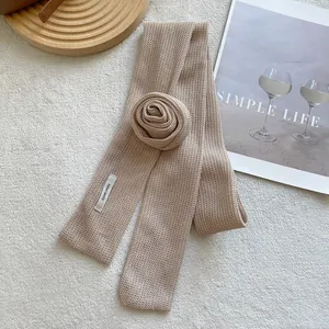 Detailed macro of a handmade knit silk scarf with a 3D fabric rose flower and white label