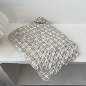Detail of beige and taupe plaid knit scarf featuring natural frayed fringe edges