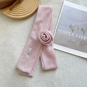 Close-up of pink knit floral neck scarf featuring a handmade rose and woven label