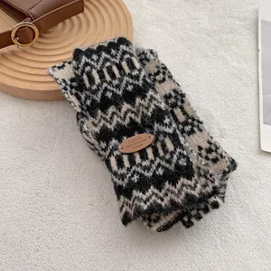Detail van gebreide Fair Isle sjaal met vintage patroon en decoratieve lederen patch